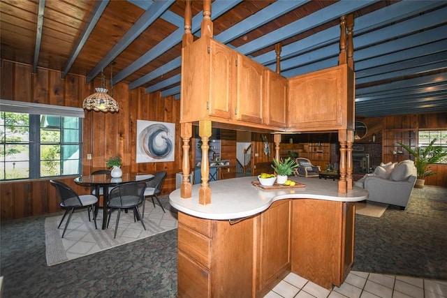 kitchen with beam ceiling, light countertops, wooden walls, and light tile patterned floors