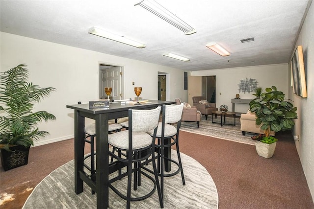 dining room with baseboards, visible vents, and dark carpet