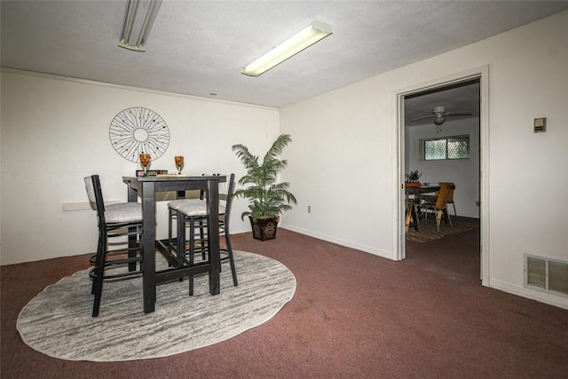 dining room with dark carpet, visible vents, and baseboards