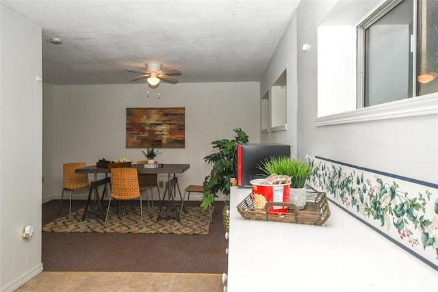 carpeted dining space with tile patterned flooring, baseboards, and a ceiling fan