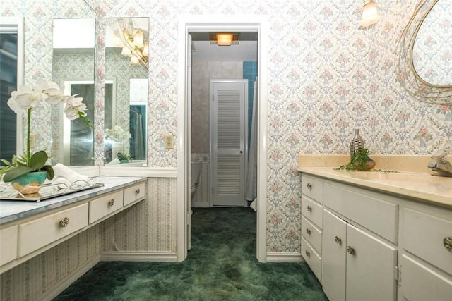 bathroom with wallpapered walls, baseboards, and vanity