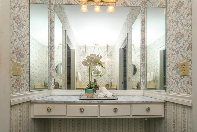 bathroom featuring vanity and wallpapered walls