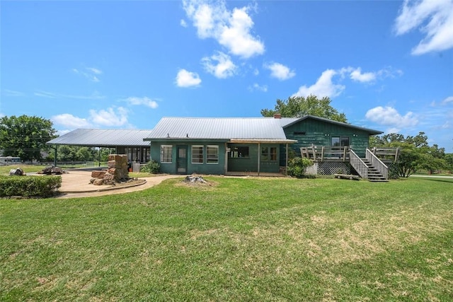 rear view of house featuring metal roof, a yard, a carport, and a deck