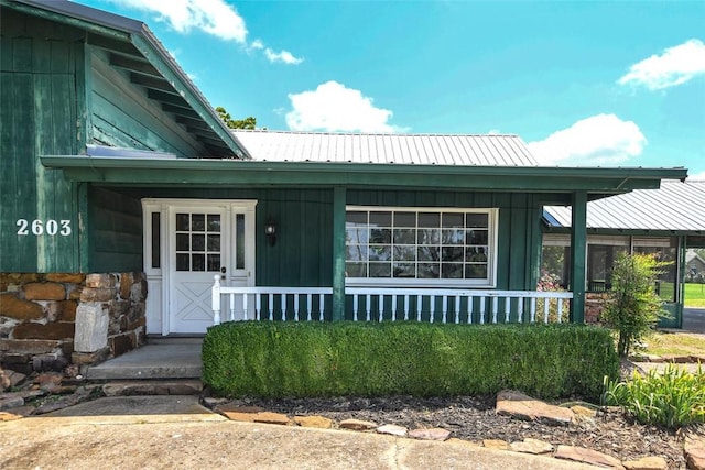 view of front facade featuring board and batten siding, covered porch, and metal roof