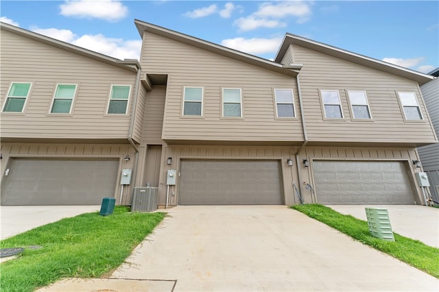 townhome / multi-family property featuring central air condition unit and a garage