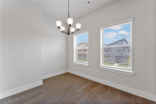 empty room with a chandelier and dark hardwood / wood-style flooring