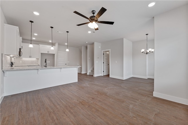 kitchen featuring white cabinets, light stone countertops, ceiling fan with notable chandelier, and dark hardwood / wood-style flooring