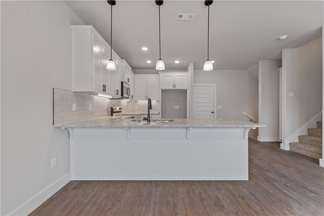 kitchen featuring white cabinets, decorative light fixtures, and wood-type flooring