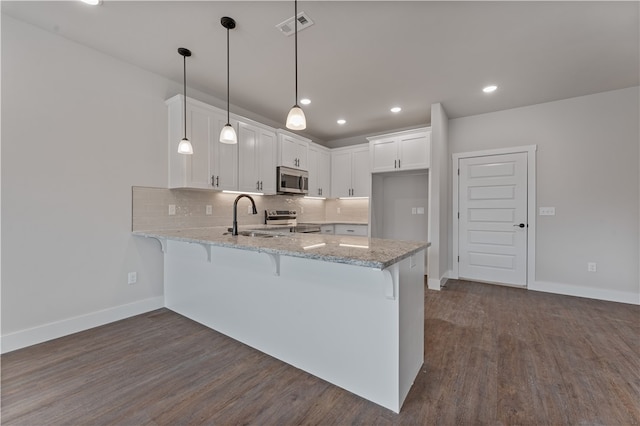 kitchen featuring sink, stainless steel appliances, pendant lighting, white cabinets, and dark wood-type flooring