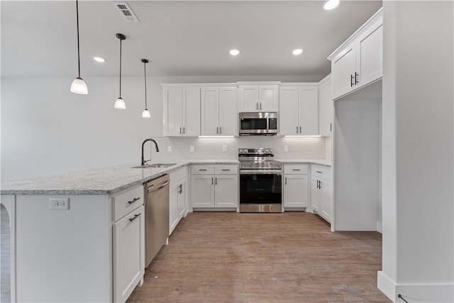 kitchen featuring kitchen peninsula, white cabinetry, sink, pendant lighting, and stainless steel appliances