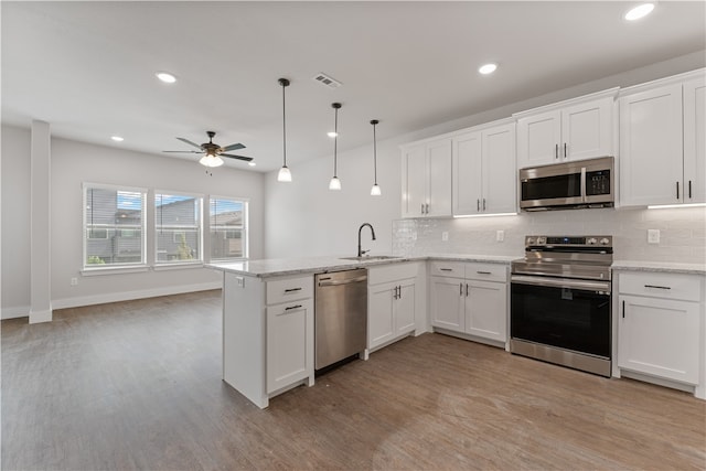 kitchen featuring white cabinetry, pendant lighting, appliances with stainless steel finishes, and kitchen peninsula