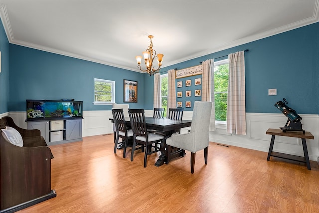 dining space featuring light hardwood / wood-style floors, crown molding, and a chandelier