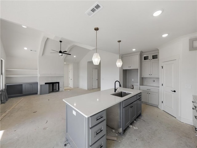 kitchen featuring a center island with sink, lofted ceiling, hanging light fixtures, sink, and ceiling fan