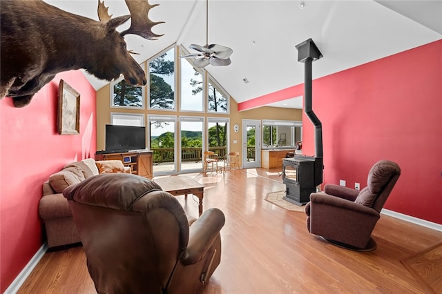 living room featuring high vaulted ceiling, wood-type flooring, ceiling fan, and a wood stove