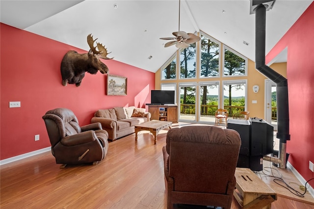 living room featuring high vaulted ceiling, wood-type flooring, ceiling fan, and a wood stove