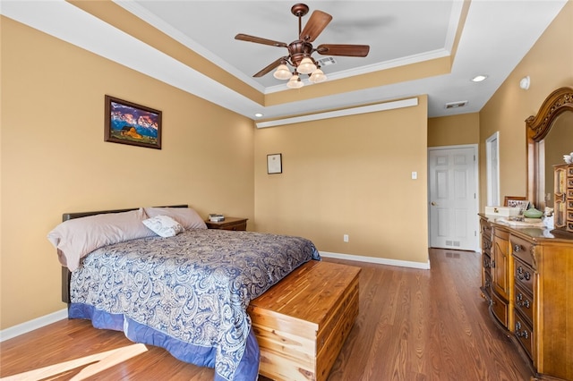 bedroom featuring crown molding, ceiling fan, a tray ceiling, and hardwood / wood-style floors