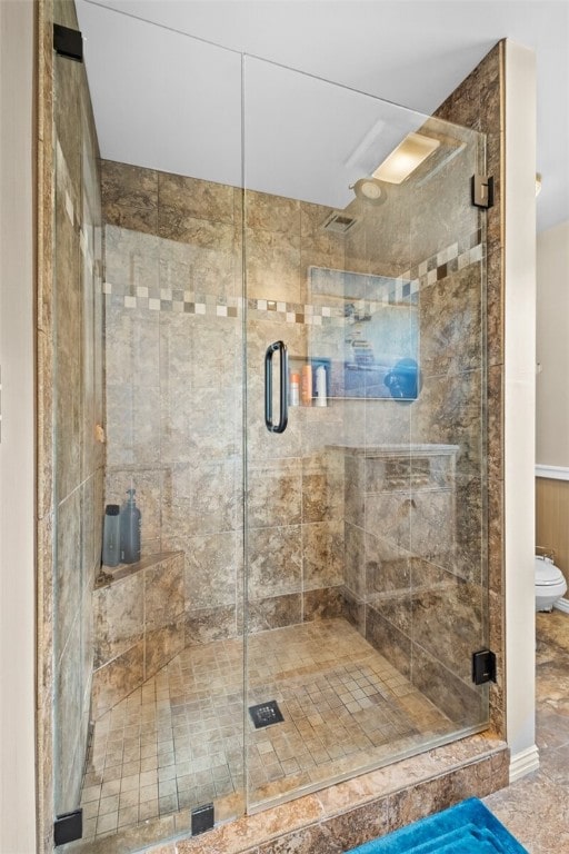 bathroom featuring tile flooring, toilet, and a shower with door