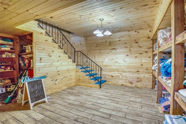 stairs with hardwood / wood-style flooring, an inviting chandelier, wood ceiling, and wood walls