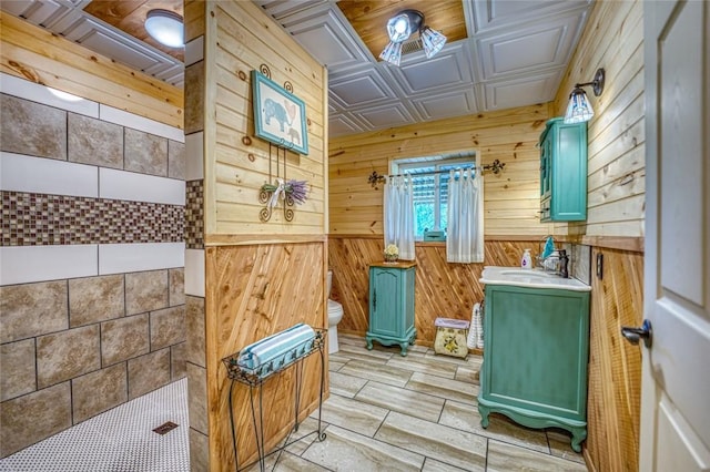 bathroom with vanity, toilet, a shower, and wooden walls