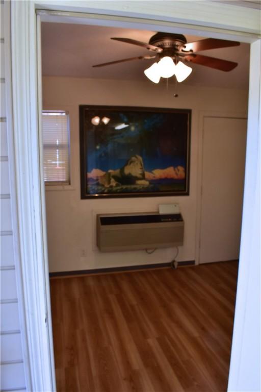 interior space with a wall mounted air conditioner and dark hardwood / wood-style flooring