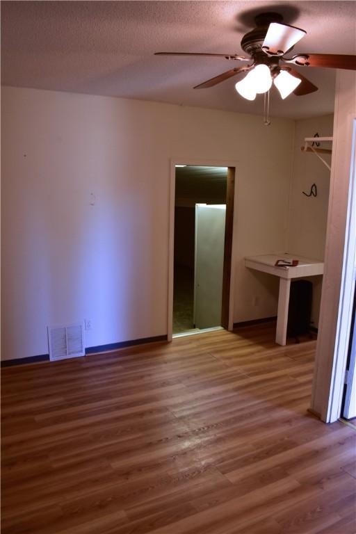 unfurnished room featuring hardwood / wood-style floors, ceiling fan, and a textured ceiling