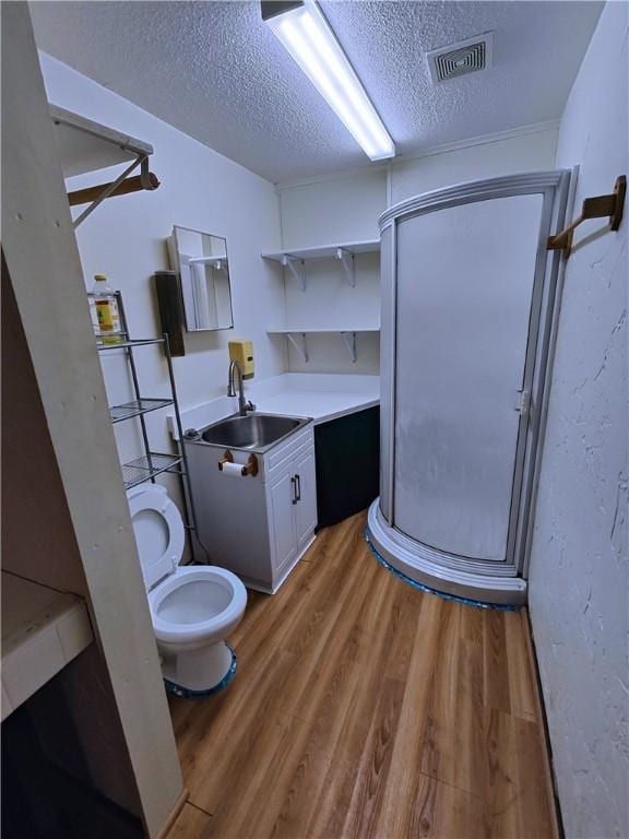 bathroom featuring walk in shower, hardwood / wood-style floors, a textured ceiling, toilet, and vanity