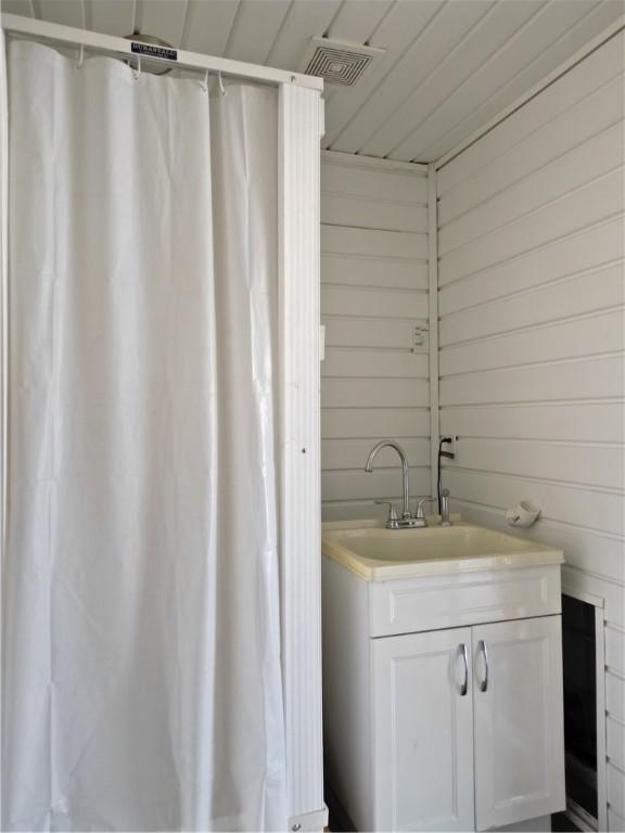 bathroom featuring vanity and wooden walls