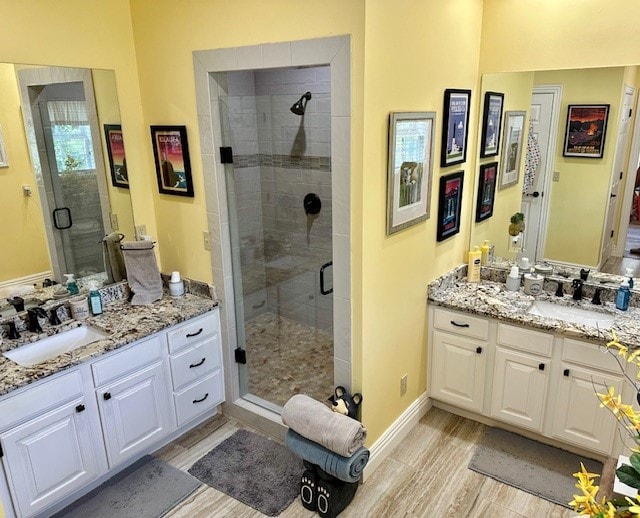 bathroom featuring a shower with shower door and vanity