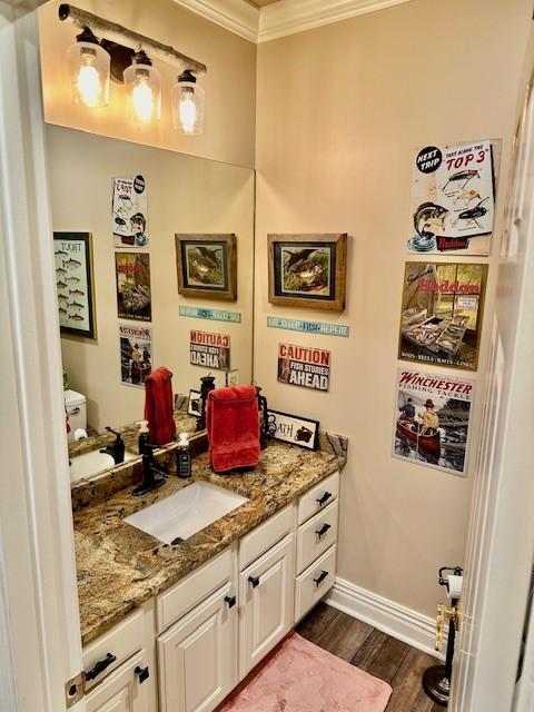 bathroom featuring vanity, ornamental molding, baseboards, and wood finished floors