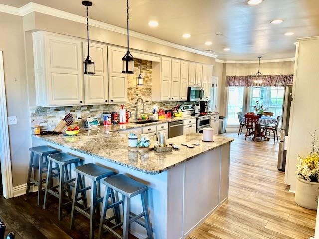 kitchen featuring a sink, tasteful backsplash, appliances with stainless steel finishes, and light wood finished floors