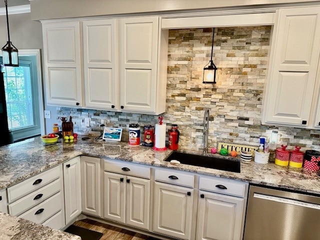 kitchen featuring decorative light fixtures, light stone countertops, hardwood / wood-style floors, and stainless steel dishwasher