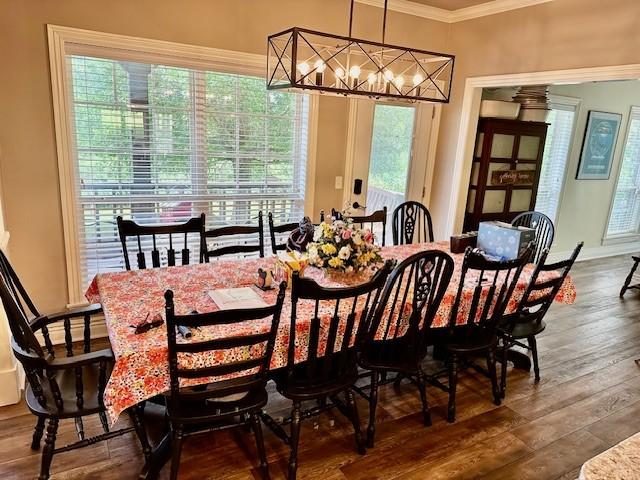 dining room featuring baseboards, crown molding, wood finished floors, and a chandelier
