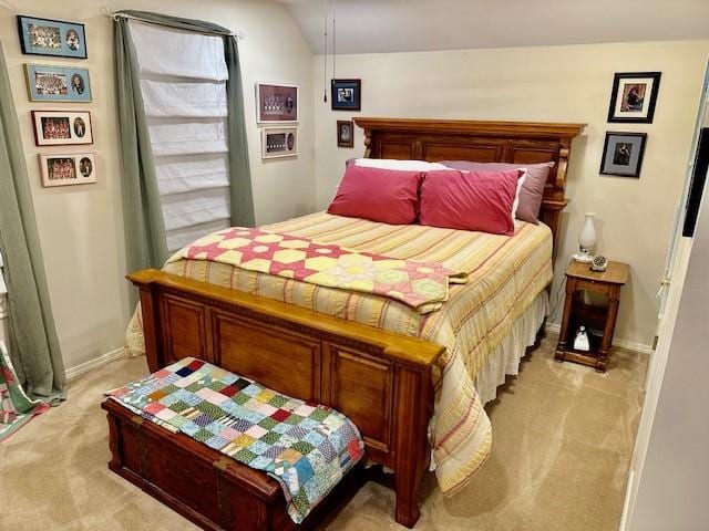bedroom with baseboards, lofted ceiling, and light colored carpet