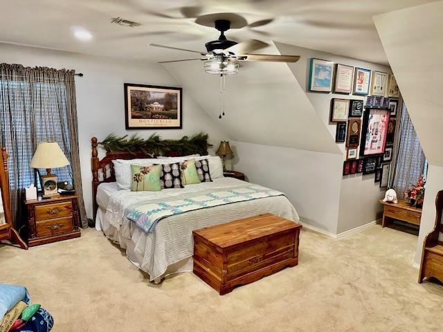carpeted bedroom featuring a ceiling fan, baseboards, lofted ceiling, and visible vents