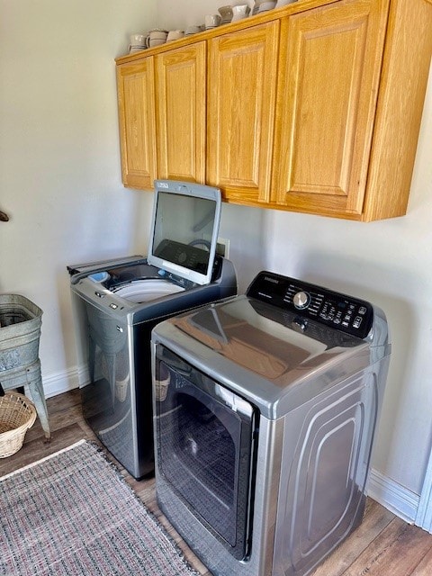 clothes washing area featuring independent washer and dryer, washer hookup, light wood-type flooring, and cabinets