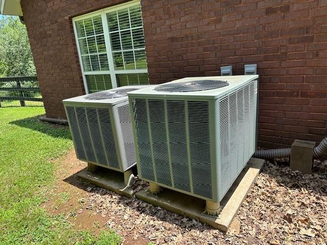 details featuring central air condition unit, fence, and brick siding
