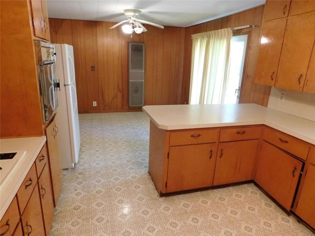 kitchen with ceiling fan, white appliances, kitchen peninsula, and wooden walls