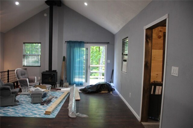 living room with high vaulted ceiling, a healthy amount of sunlight, a wood stove, and wood-type flooring