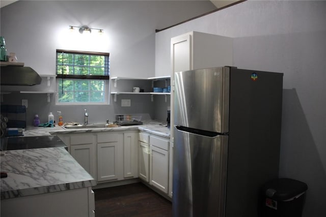 kitchen with dark wood-type flooring, sink, stainless steel fridge, white cabinets, and light stone counters