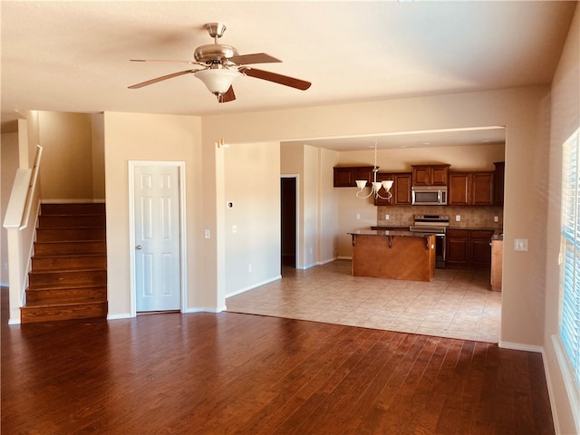 kitchen featuring decorative backsplash, stainless steel appliances, light hardwood / wood-style flooring, hanging light fixtures, and a breakfast bar area