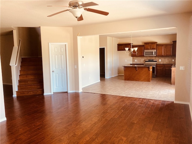 kitchen featuring a breakfast bar, tasteful backsplash, wood finished floors, stainless steel appliances, and brown cabinetry