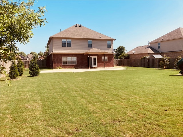 rear view of property featuring a patio, a yard, and a fenced backyard