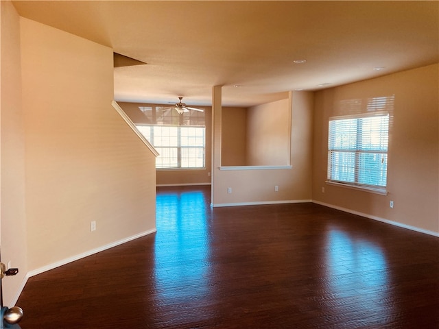 empty room with a ceiling fan, wood finished floors, baseboards, and a wealth of natural light