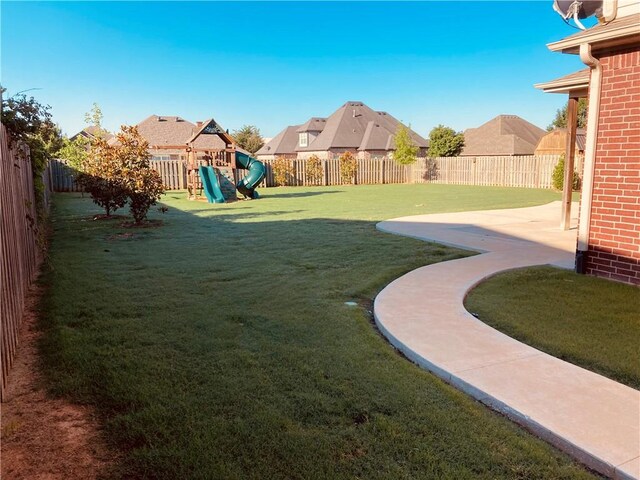 view of yard with a residential view, a patio, a fenced backyard, and a playground