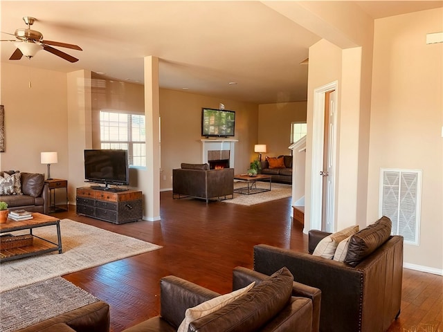 living area with visible vents, baseboards, a tile fireplace, a ceiling fan, and dark wood-style flooring