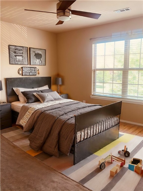 bedroom featuring wood finished floors, visible vents, multiple windows, and ceiling fan