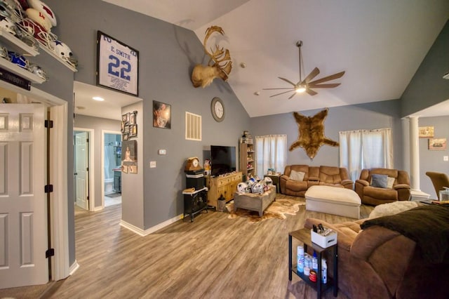 living room with ceiling fan, wood-type flooring, ornate columns, and high vaulted ceiling