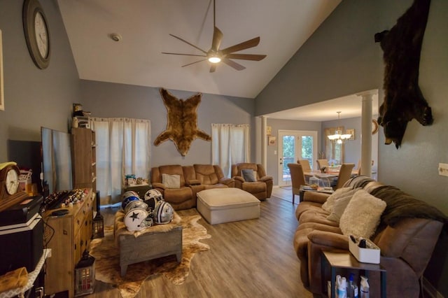 living room featuring ceiling fan with notable chandelier, light hardwood / wood-style floors, ornate columns, and high vaulted ceiling