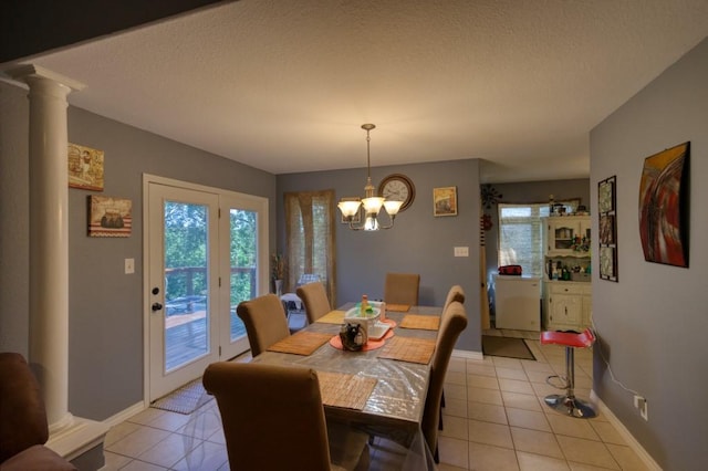 dining room with decorative columns, light tile patterned floors, a textured ceiling, and a notable chandelier