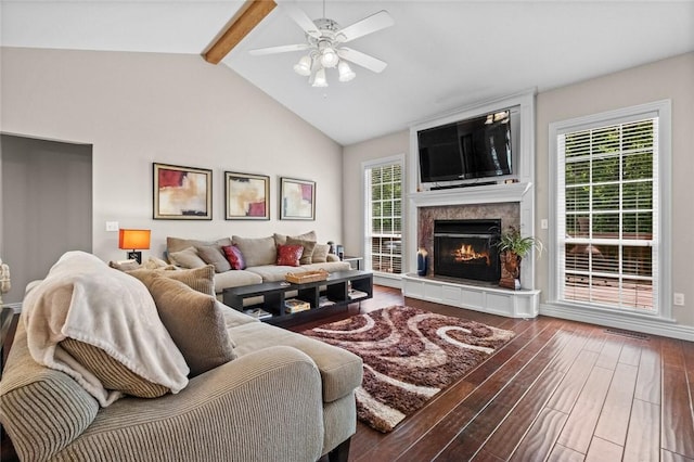 living room featuring hardwood / wood-style floors, vaulted ceiling with beams, a tile fireplace, and a healthy amount of sunlight